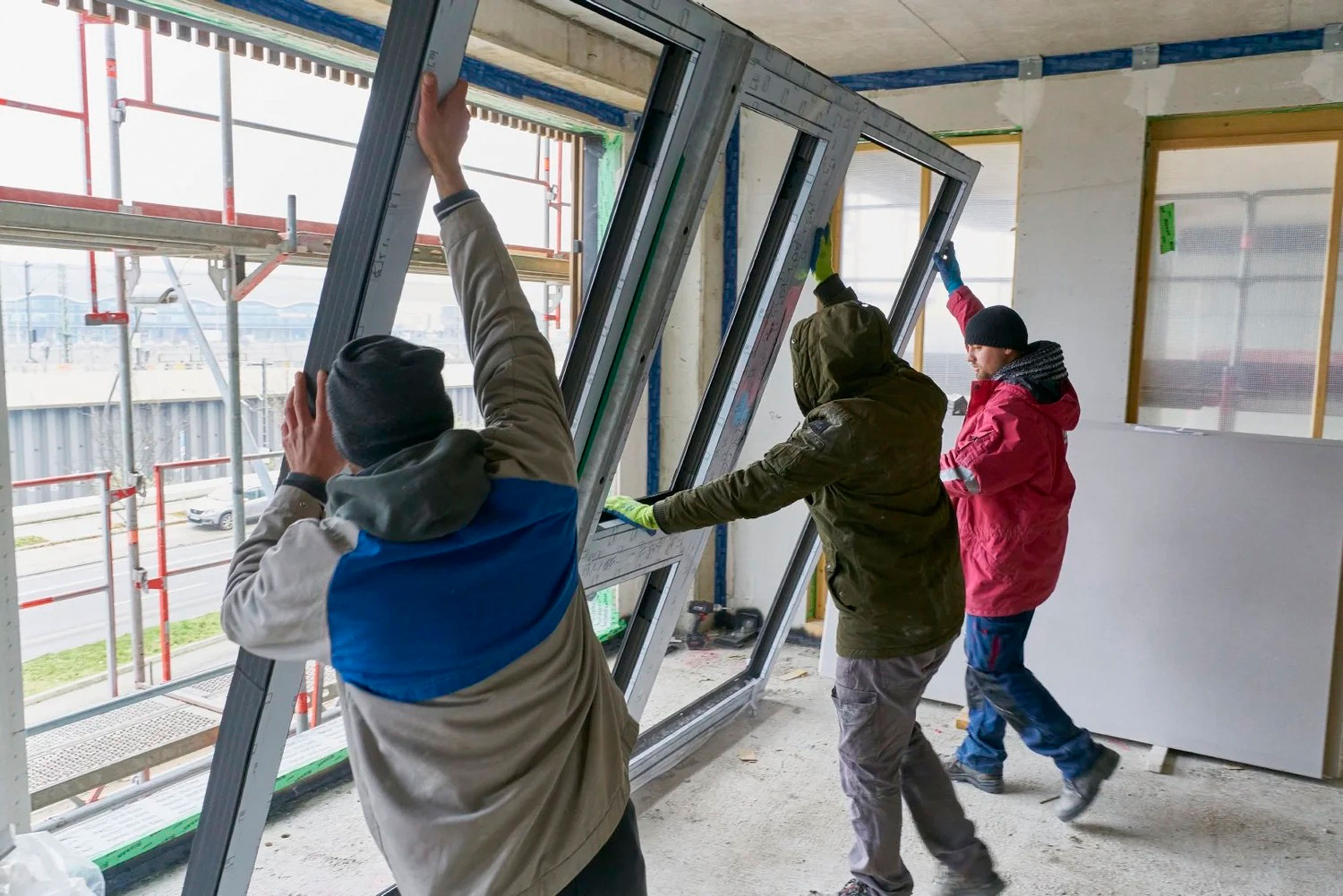 Arbeiter bei der Installation eines neuen Fenster-Elements, das den Nutzen der Immobilie erweitert.
