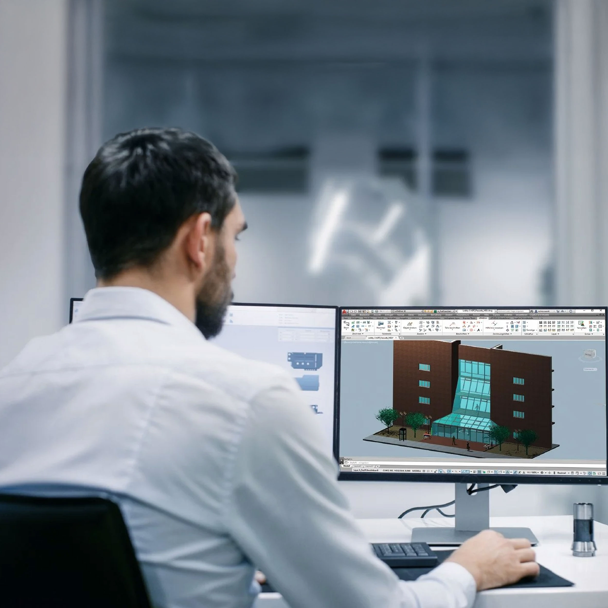 Ein Ingenieur oder Architekt arbeitet am Computer an einer technischen 3D-Zeichnung der Fassade eines modernen Gebäudes, um den detaillierten Planungsprozess einer energetischen Fassadensanierung zu veranschaulichen.